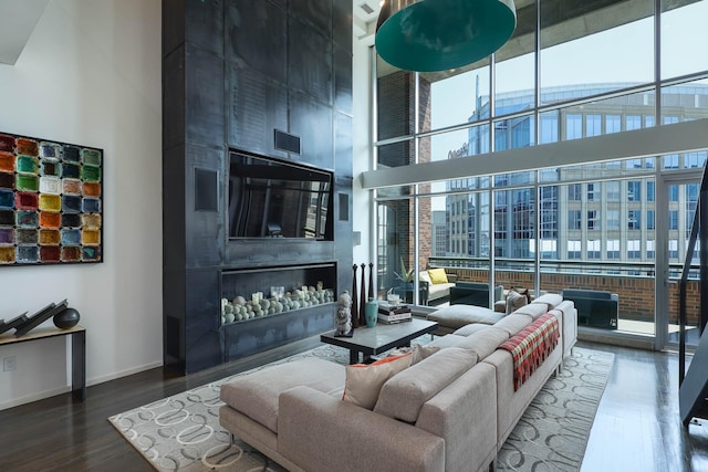 living room featuring dark wood-type flooring, a towering ceiling, and a fireplace