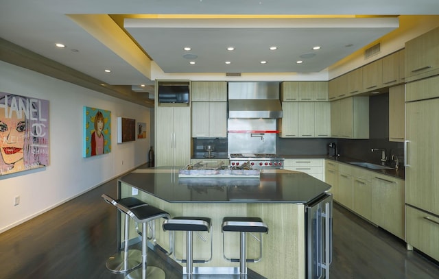 kitchen with a spacious island, stove, wall chimney range hood, a breakfast bar, and sink