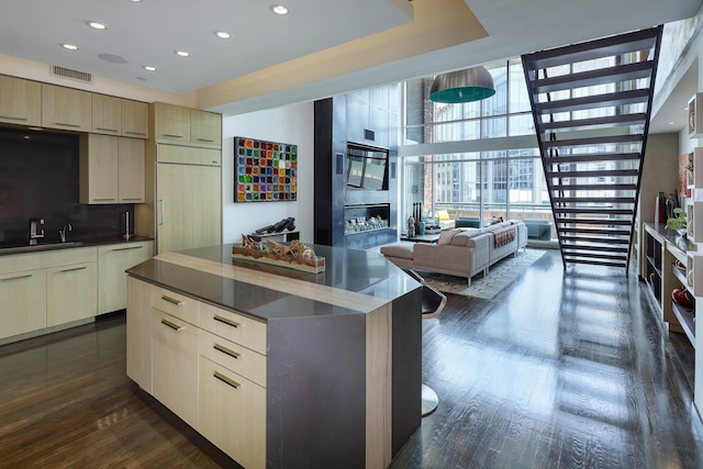 kitchen with cream cabinets, dark hardwood / wood-style flooring, a kitchen island, and paneled built in fridge