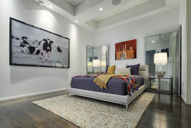 bedroom with dark hardwood / wood-style flooring and a towering ceiling