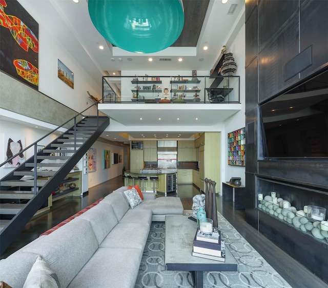 living room featuring a high ceiling, dark hardwood / wood-style floors, and a tray ceiling