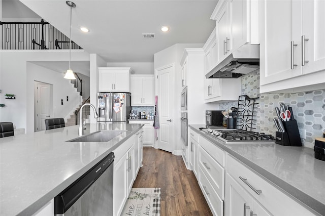 kitchen with decorative light fixtures, decorative backsplash, sink, white cabinetry, and stainless steel appliances