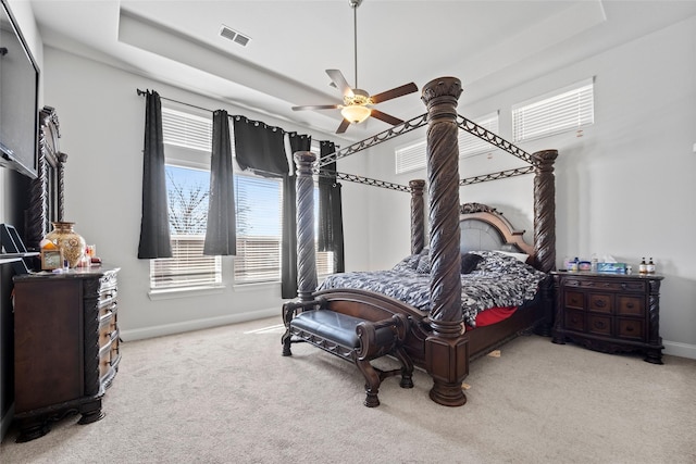 bedroom with ceiling fan, light colored carpet, and a tray ceiling