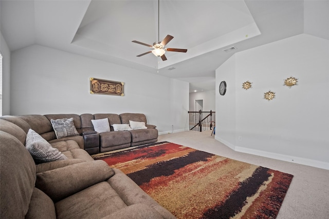 living room with ceiling fan, a raised ceiling, and light carpet