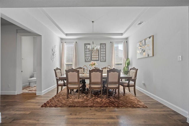 dining space with dark hardwood / wood-style floors and a notable chandelier