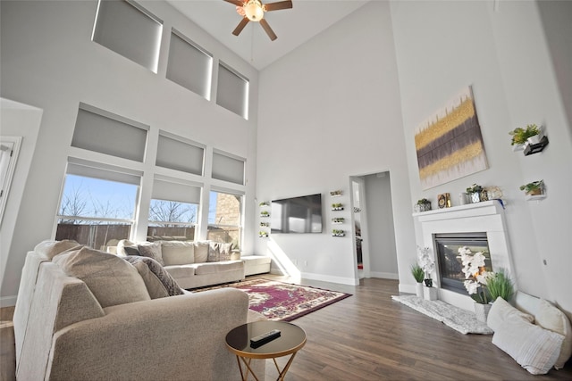 living room featuring dark wood-type flooring, ceiling fan, and a towering ceiling