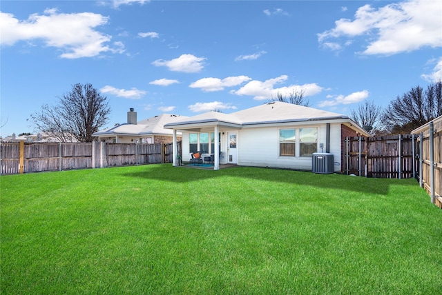 rear view of house featuring central air condition unit and a lawn