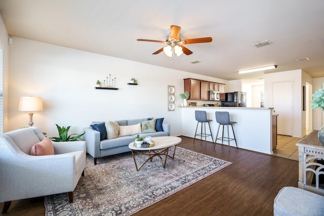 living room featuring ceiling fan and dark hardwood / wood-style floors