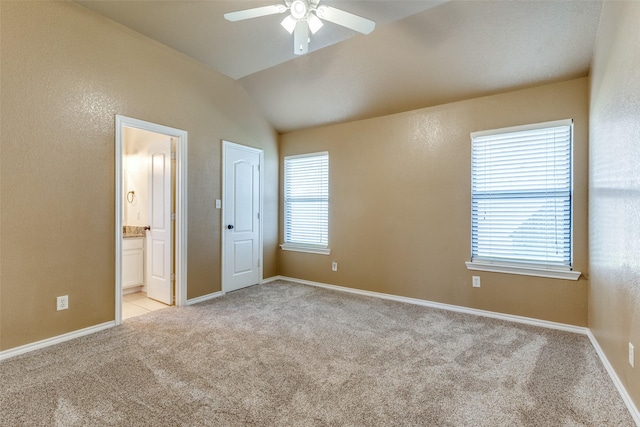 unfurnished bedroom with ceiling fan, multiple windows, ensuite bathroom, and lofted ceiling