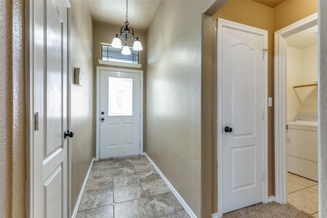 doorway to outside featuring a textured ceiling, an inviting chandelier, and washer / clothes dryer