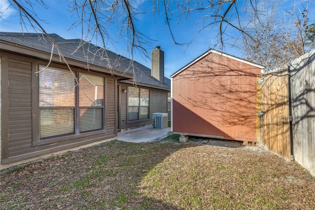 exterior space featuring a shed, cooling unit, a patio area, and a yard