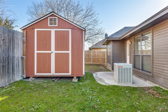 view of outdoor structure featuring a lawn and central AC