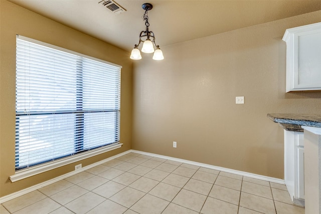 unfurnished dining area with light tile patterned floors and an inviting chandelier