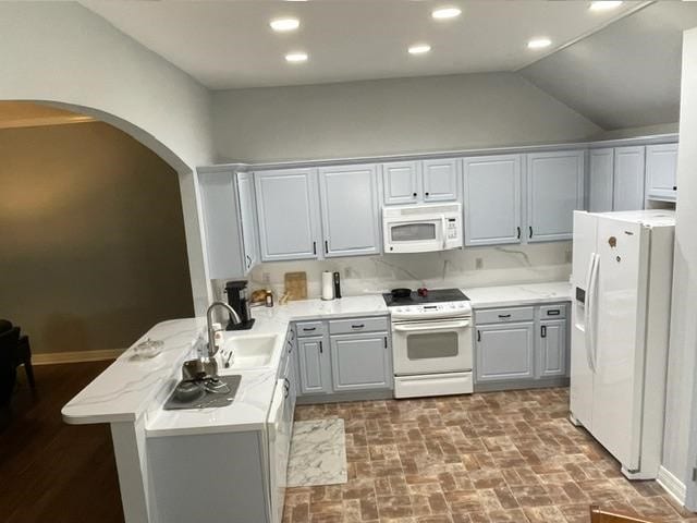 kitchen featuring white appliances, lofted ceiling, sink, gray cabinets, and kitchen peninsula