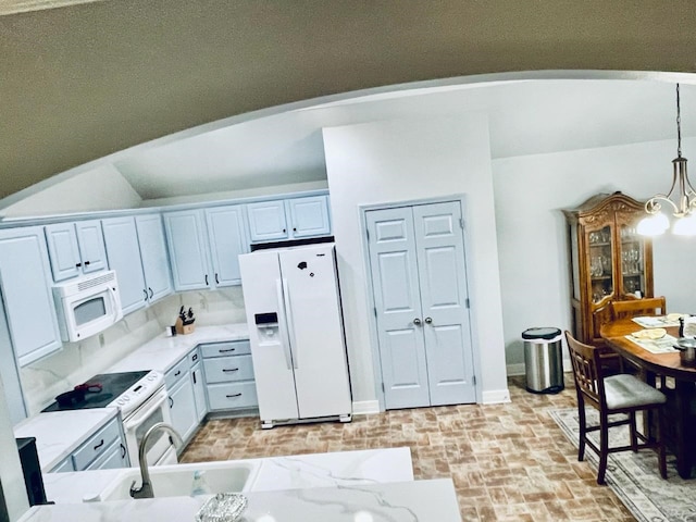 kitchen with white appliances, tasteful backsplash, white cabinetry, decorative light fixtures, and an inviting chandelier