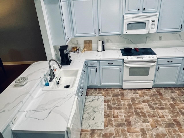 kitchen featuring light stone countertops, sink, white appliances, and gray cabinetry