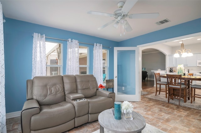 living room with ceiling fan with notable chandelier