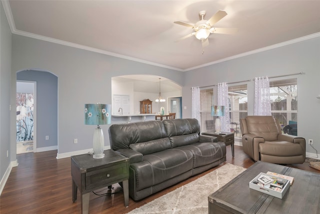 living room featuring crown molding, dark wood-type flooring, and ceiling fan with notable chandelier