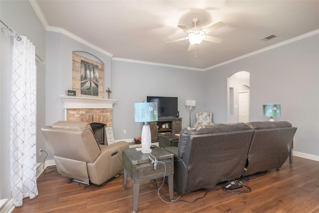 living room featuring hardwood / wood-style flooring, crown molding, a stone fireplace, and ceiling fan