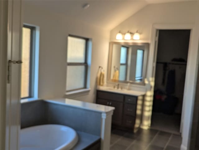 bathroom with vaulted ceiling, tile patterned flooring, a bath, and vanity