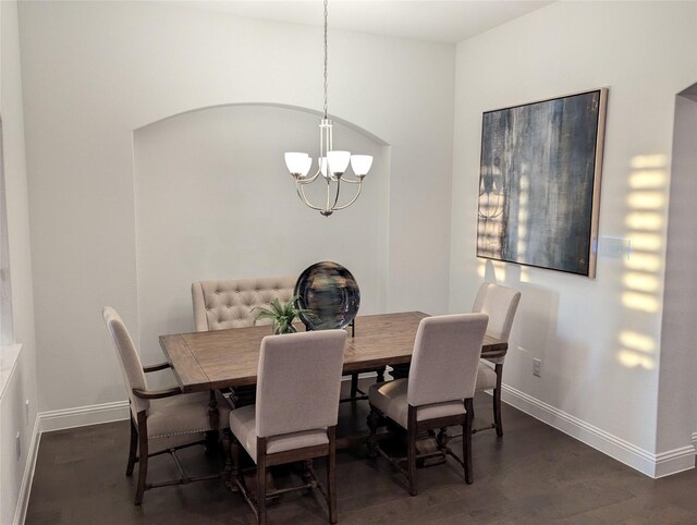 dining area featuring dark wood-type flooring and a notable chandelier