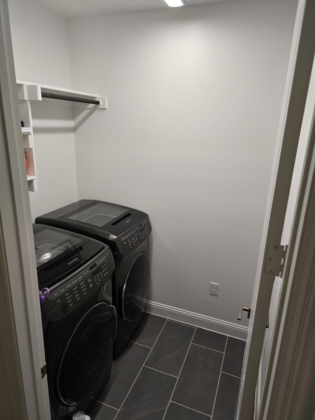 laundry area featuring laundry area, dark tile patterned floors, baseboards, and separate washer and dryer