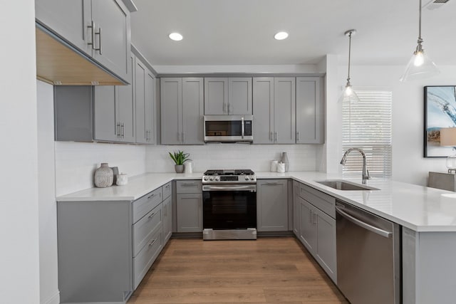 kitchen with decorative light fixtures, sink, gray cabinets, and stainless steel appliances