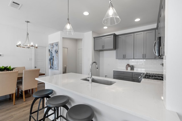 kitchen with hanging light fixtures, kitchen peninsula, dark hardwood / wood-style floors, and sink