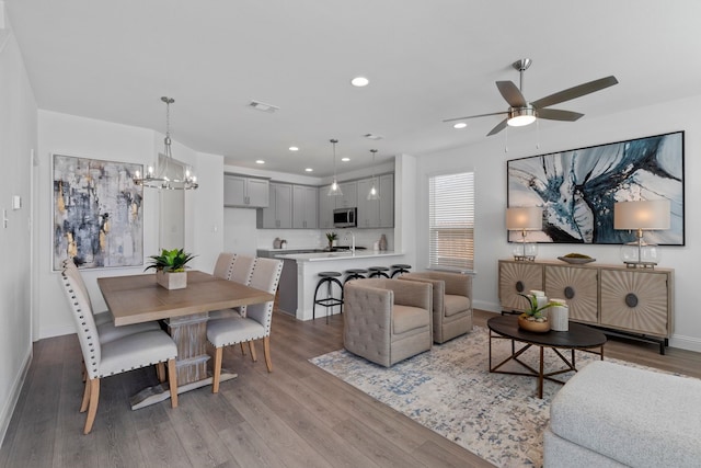 living room with ceiling fan with notable chandelier and light hardwood / wood-style floors