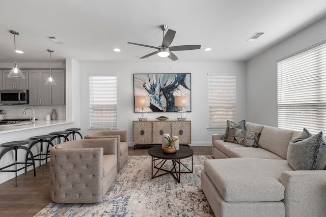 living room featuring ceiling fan, a healthy amount of sunlight, sink, and light hardwood / wood-style floors