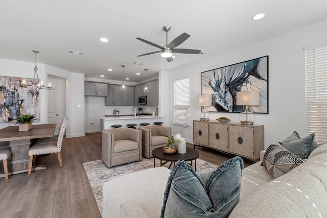 living room with light hardwood / wood-style floors and ceiling fan with notable chandelier