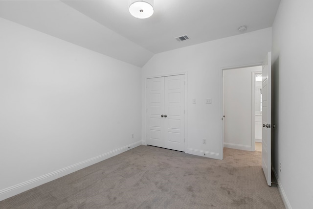 unfurnished bedroom with lofted ceiling, light colored carpet, and a closet