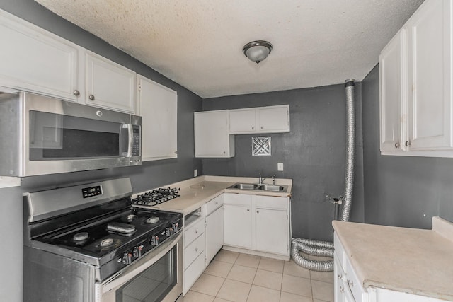 kitchen featuring white cabinets, appliances with stainless steel finishes, sink, and light tile patterned floors