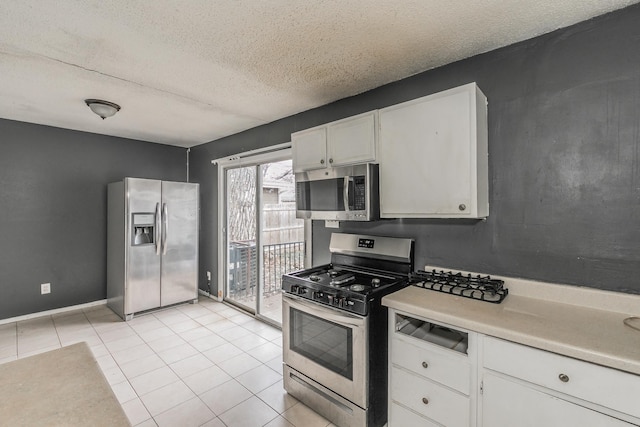 kitchen with light tile patterned floors, white cabinetry, appliances with stainless steel finishes, and a textured ceiling