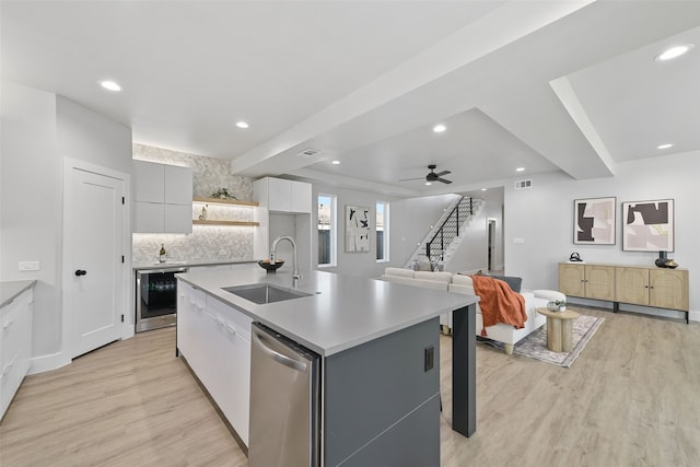 kitchen with white cabinetry, a center island with sink, ceiling fan, stainless steel dishwasher, and sink