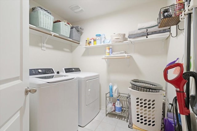 clothes washing area featuring light tile patterned floors and washer and clothes dryer