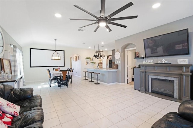 living room with ceiling fan with notable chandelier, light tile patterned floors, and lofted ceiling