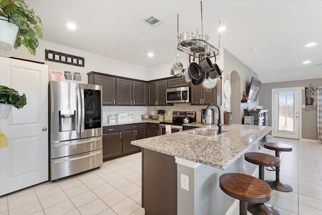 kitchen featuring stainless steel appliances, decorative backsplash, a kitchen breakfast bar, dark brown cabinetry, and sink