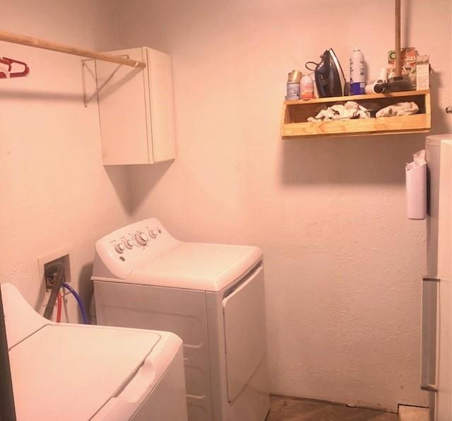 clothes washing area featuring cabinets and separate washer and dryer