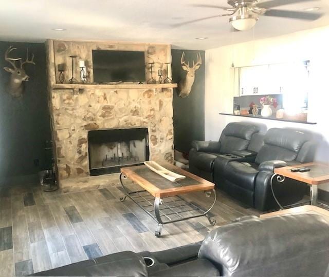 living room featuring ceiling fan, a fireplace, and hardwood / wood-style flooring