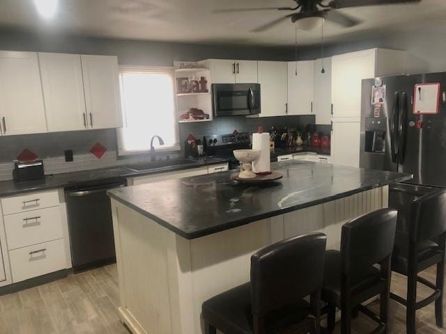 kitchen featuring white cabinetry, a center island, black appliances, light hardwood / wood-style flooring, and sink