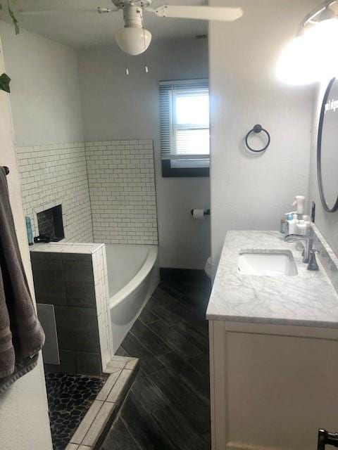 bathroom featuring ceiling fan, vanity, and a bathing tub