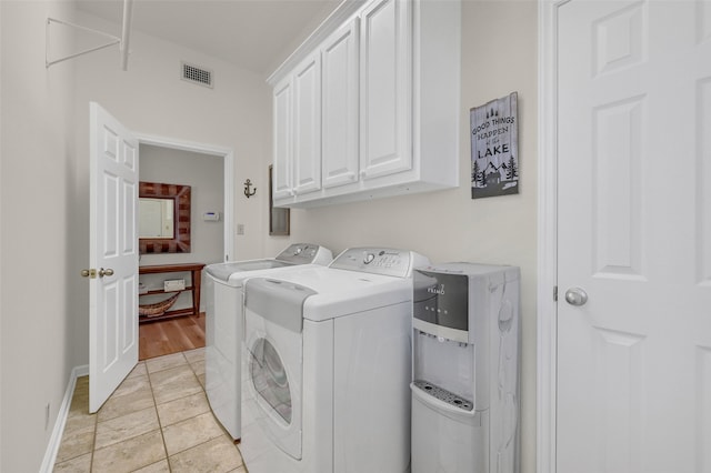 clothes washing area with cabinets, washing machine and dryer, and light tile patterned flooring