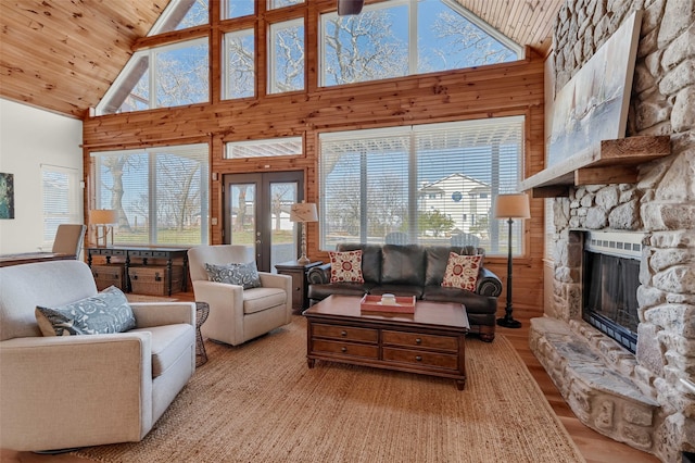 living room with wood ceiling, a fireplace, high vaulted ceiling, and wood walls