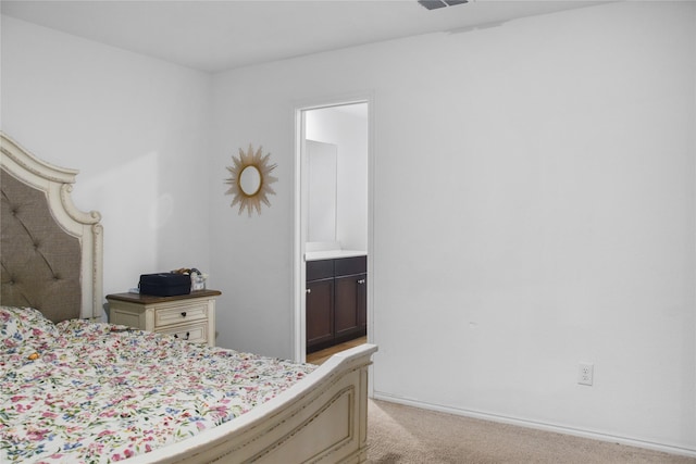 bedroom featuring light colored carpet and connected bathroom