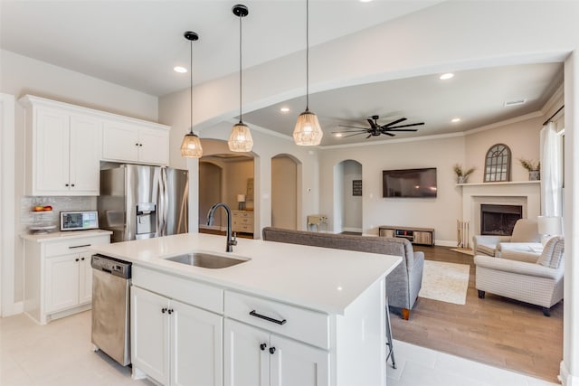 kitchen featuring sink, white cabinets, stainless steel appliances, and a kitchen island with sink