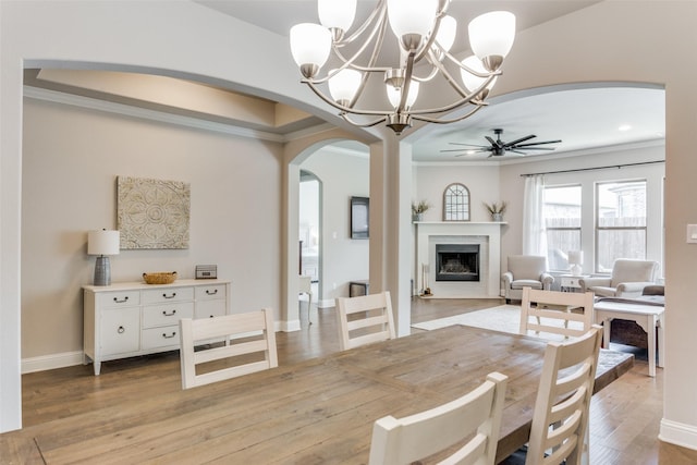 dining room featuring crown molding, light wood-type flooring, and ceiling fan with notable chandelier