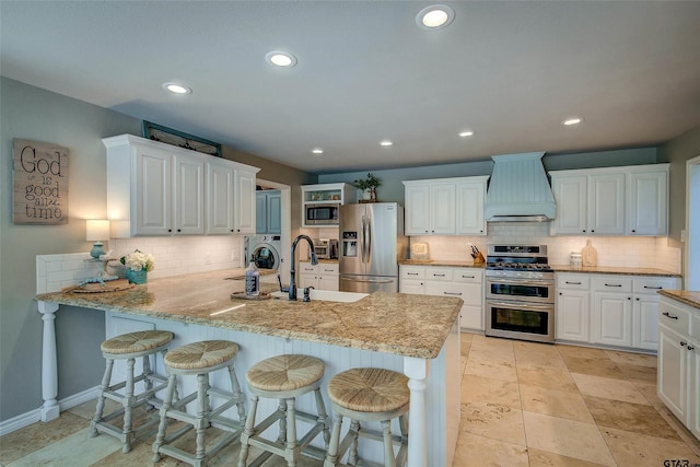 kitchen with kitchen peninsula, appliances with stainless steel finishes, white cabinetry, and custom range hood