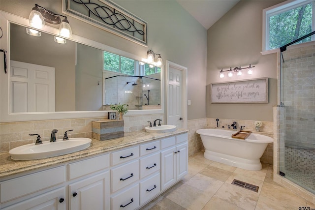 bathroom with separate shower and tub, vanity, tile walls, lofted ceiling, and tile patterned floors