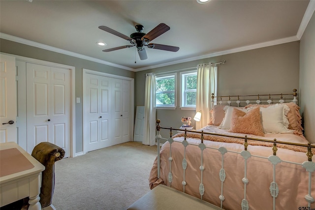 bedroom featuring ceiling fan, light colored carpet, two closets, and crown molding